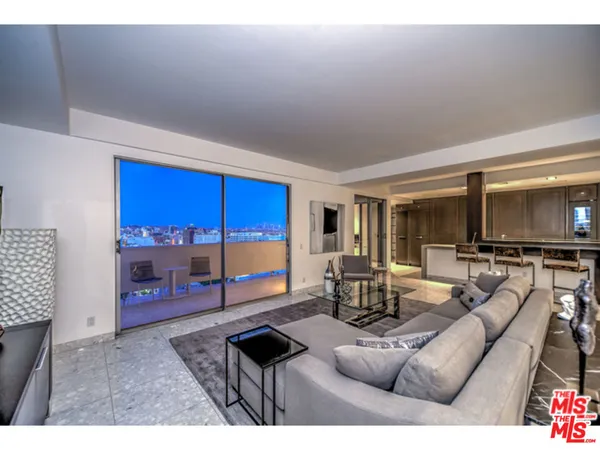 a living room with furniture a flat screen tv and floor to ceiling window