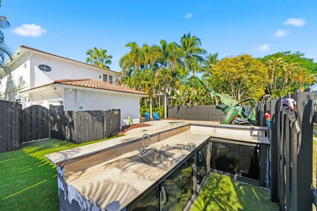 a backyard of a house with table and chairs under an umbrella