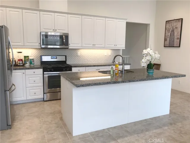 a kitchen with stainless steel appliances granite countertop a stove a sink and a microwave