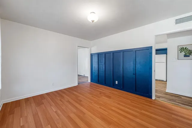 a view of empty room with wooden floor and fan