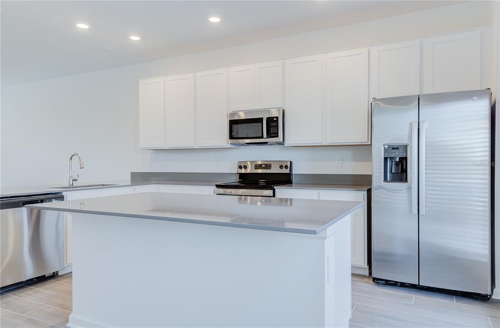 15627 Water Spring Boulevard Winter Garden, FL 34787 - Photo 15 of 45 a kitchen with granite countertop a refrigerator and a stove top oven