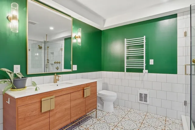 a bathroom with a double vanity sink toilet and green walls