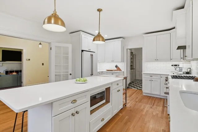 a kitchen with stainless steel appliances a stove a sink dishwasher a refrigerator white cabinets and wooden floor