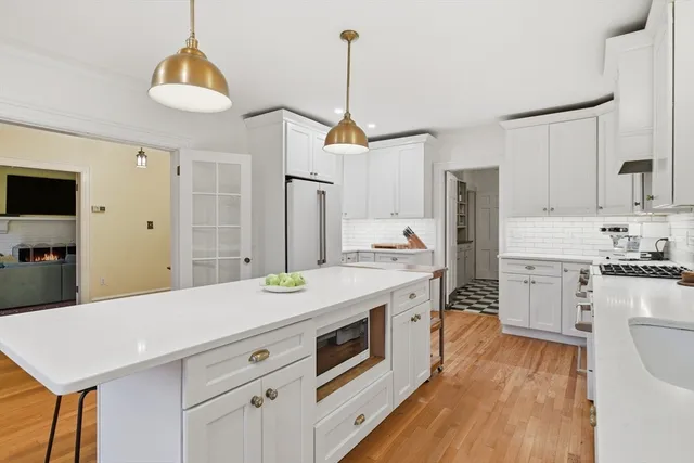 a kitchen with stainless steel appliances a stove a sink dishwasher a refrigerator white cabinets and wooden floor