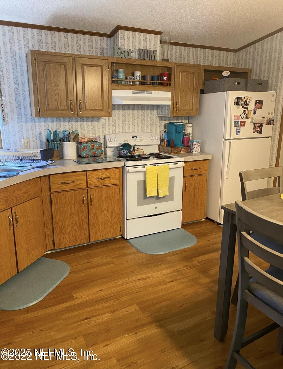 86266 Weldon Road Yulee, FL 32097 - Photo 3 of 10 a kitchen with stainless steel appliances granite countertop a sink a stove a refrigerator and island with wooden floor