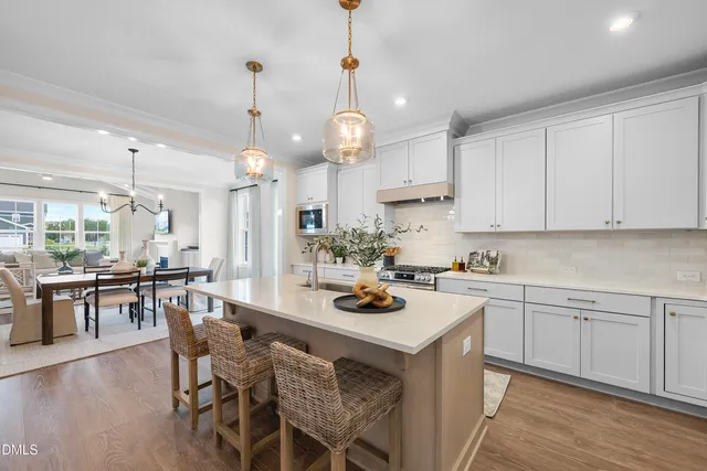a kitchen with a dining table chairs stove and white cabinets