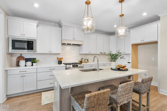 a kitchen with stainless steel appliances kitchen island granite countertop a sink a stove a dining table and chairs