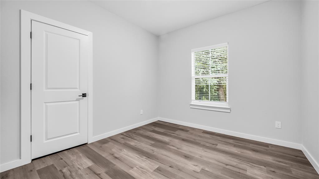716 East Chestnut Street Denison, TX 75021 - Photo 14 of 26 Room featuring wood-finish flooring, a white two-panel door with black hardware, and a window with white blinds
