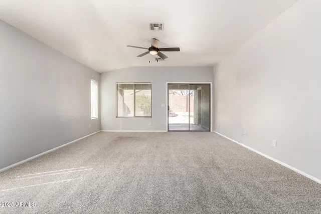 an empty room with windows and ceiling fan