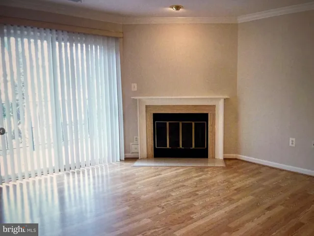 an empty room with wooden floor fireplace and windows
