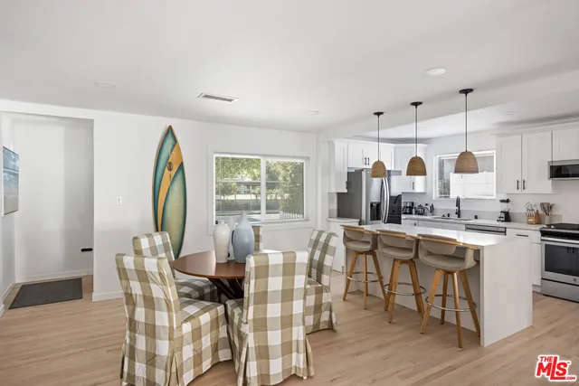 a kitchen with stainless steel appliances kitchen island granite countertop a stove a sink a dining table and chairs