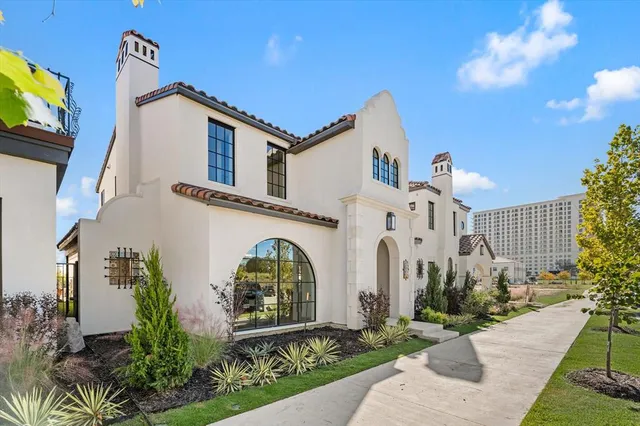 a view of a white house with many windows and plants