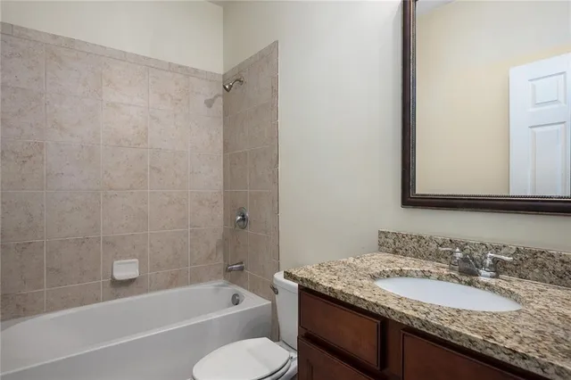 a bathroom with a granite countertop sink toilet mirror and bathtub