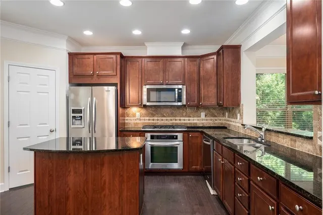 a kitchen with stainless steel appliances granite countertop a stove a sink and a refrigerator