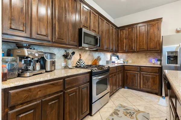 a kitchen with granite countertop wooden cabinets stainless steel appliances and a sink