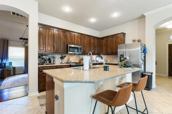 a kitchen with kitchen island granite countertop a stove a sink a refrigerator with a dining table and chairs