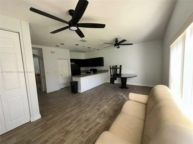 a living room with stainless steel appliances kitchen island granite countertop furniture and a refrigerator