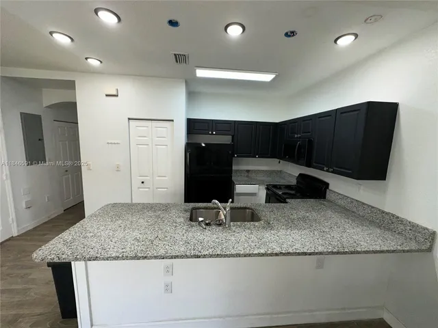 a kitchen with granite countertop a refrigerator and a sink