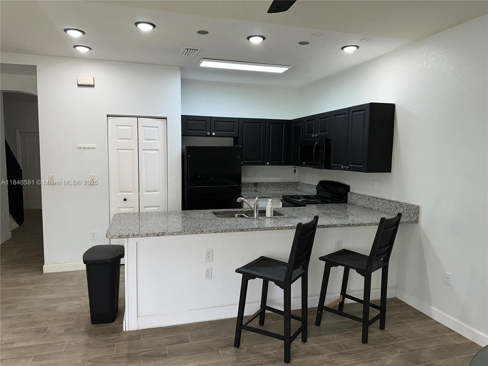 4908 Southwest 141st Avenue, Unit 3 Miramar, FL 33027 - Photo 10 of 29 a kitchen with stainless steel appliances kitchen island granite countertop a refrigerator and a stove top oven