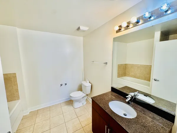 a bathroom with a granite countertop sink toilet and mirror