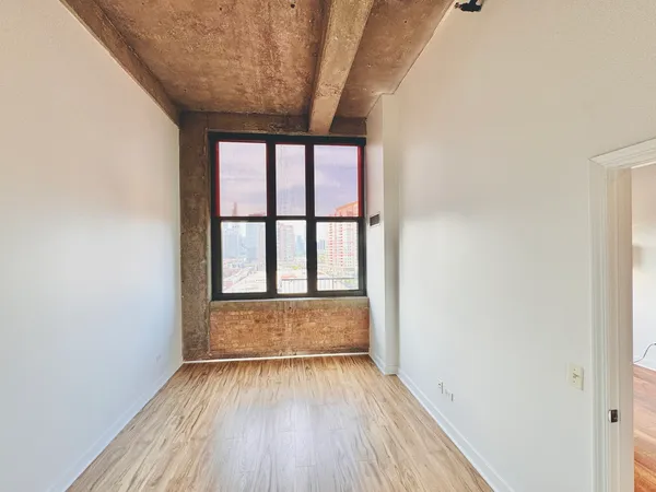 an empty room with wooden floor and windows