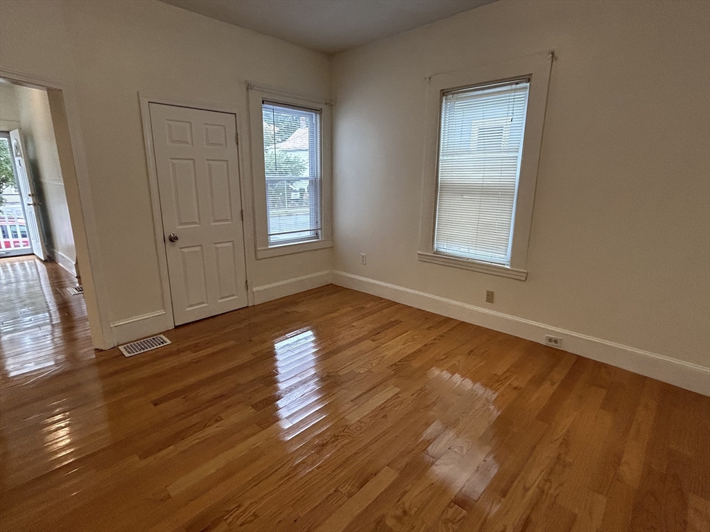 125 Spring Street, Unit 1 Medford, MA 02155 - Photo 4 of 12 an empty room with wooden floor and windows