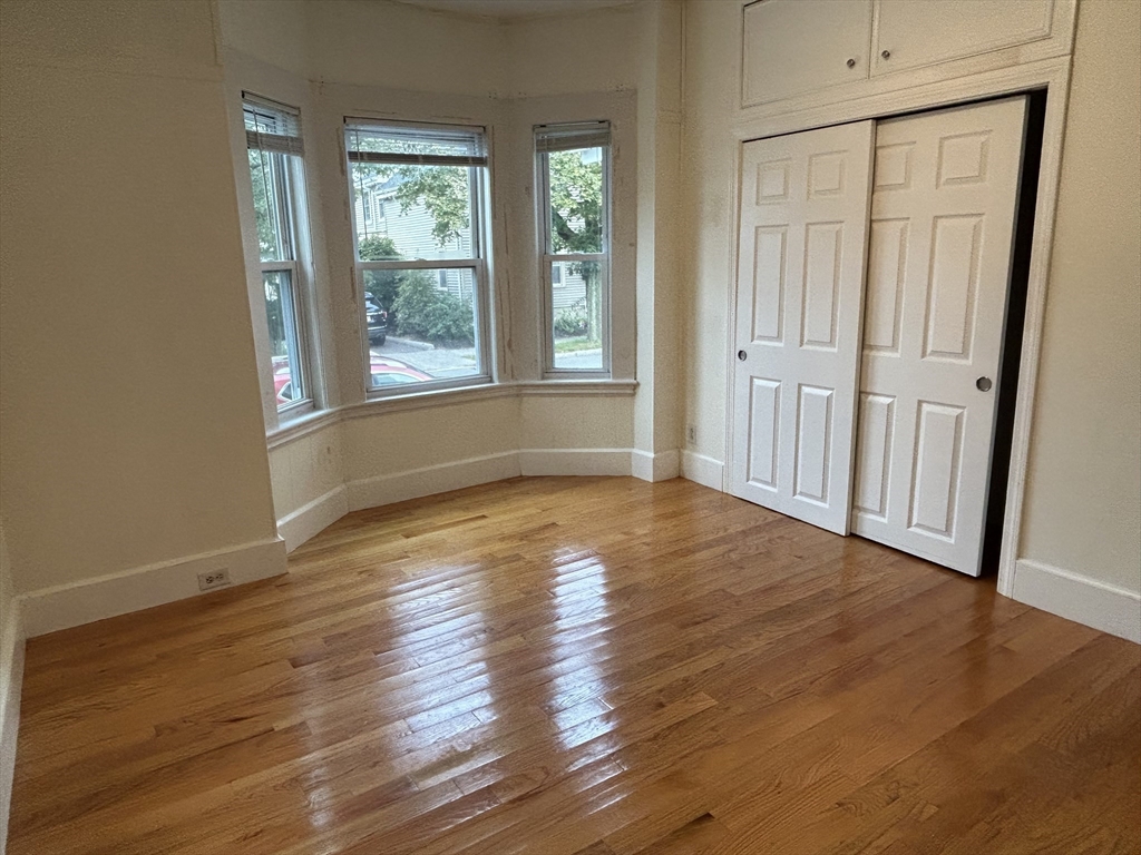 125 Spring Street, Unit 1 Medford, MA 02155 - Photo 7 of 12 a view of empty room with wooden floor and fan