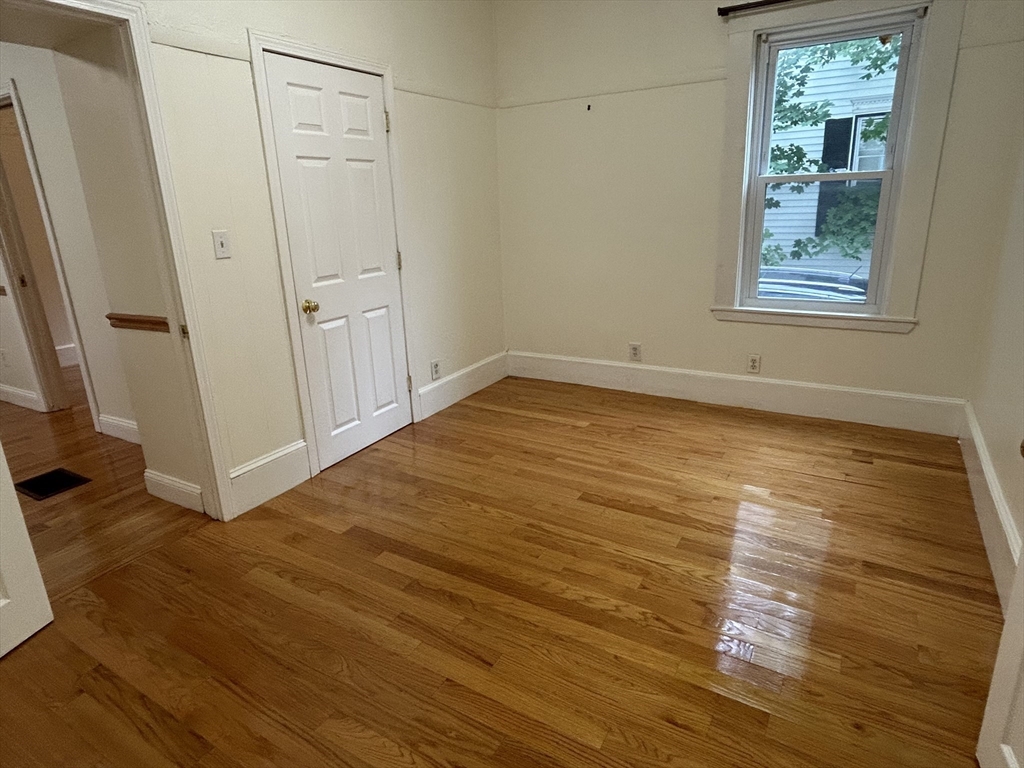 125 Spring Street, Unit 1 Medford, MA 02155 - Photo 8 of 12 a view of an empty room with wooden floor and a window