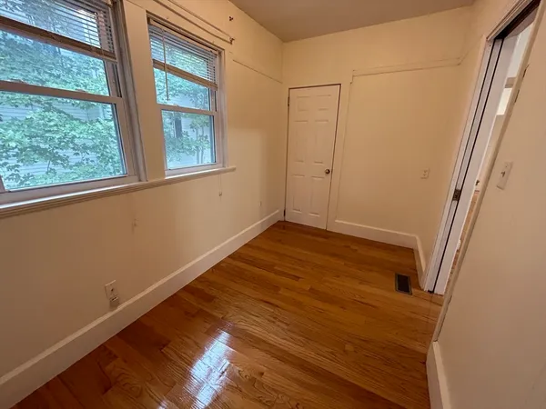 a view of empty room with wooden floor and fan