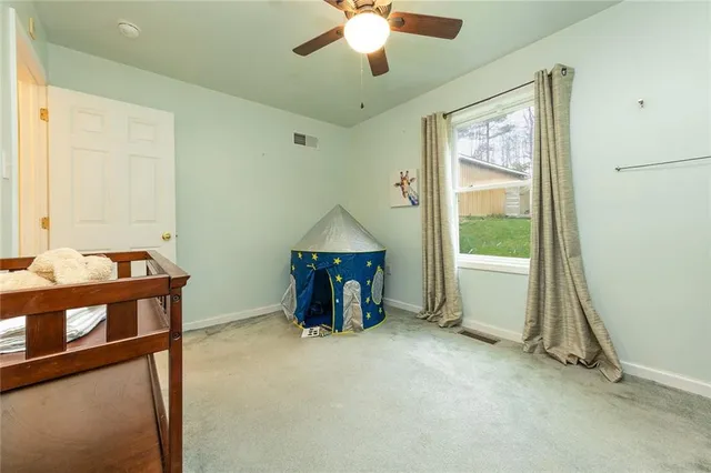 an empty room with chandelier fan and windows