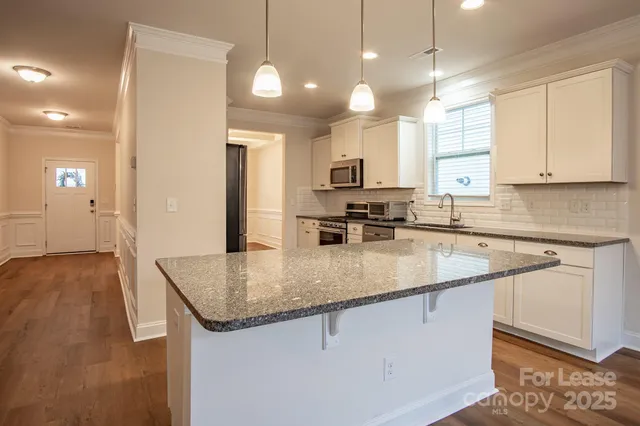 a kitchen with kitchen island granite countertop a sink a counter top space appliances and cabinets