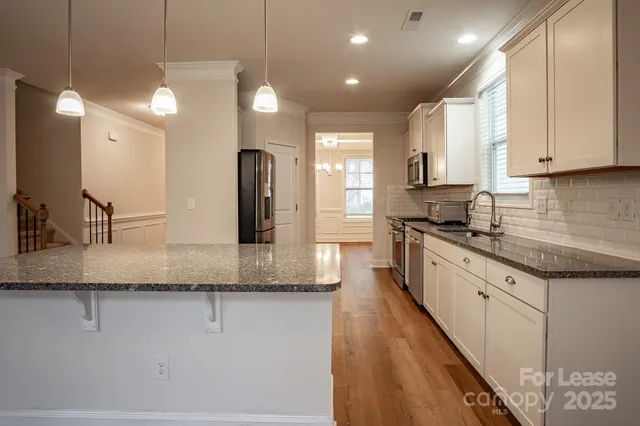 a large kitchen with granite countertop a sink a counter top space and stainless steel appliances