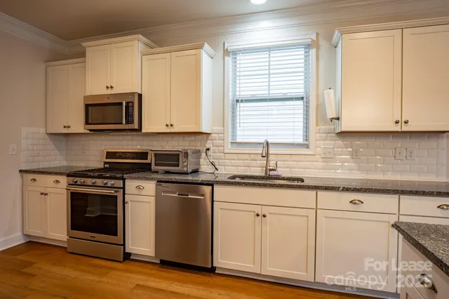 a kitchen with granite countertop cabinets stainless steel appliances and a sink