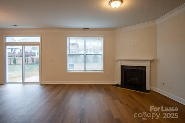 an empty room with wooden floor fireplace and windows