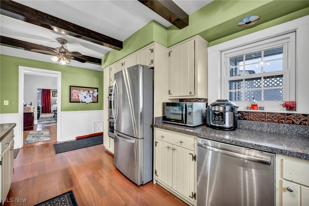 4743 Broadale Road Cleveland, OH 44109 - Photo 10 of 32 Kitchen with appliances with stainless steel finishes, beam ceiling, a wainscoted wall, wood finished floors, and a ceiling fan