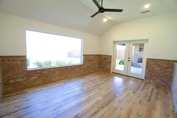 an empty room with wooden floor and windows