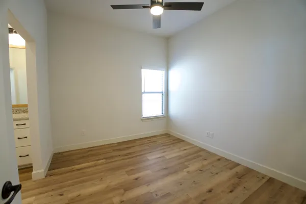 an empty room with wooden floor fan and windows