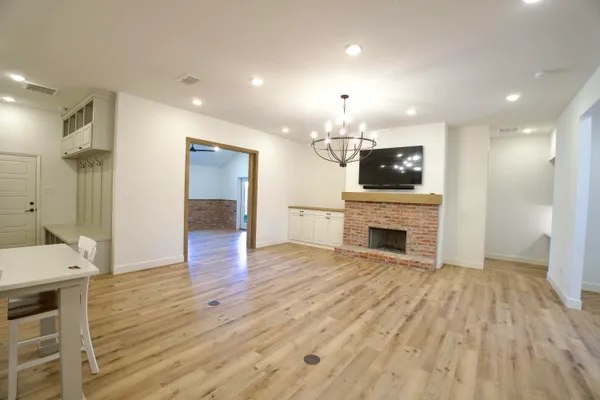 a view of a livingroom with a fireplace a chandelier and wooden floor