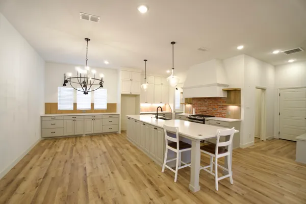 a kitchen with stainless steel appliances kitchen island granite countertop a wooden floor and white cabinets
