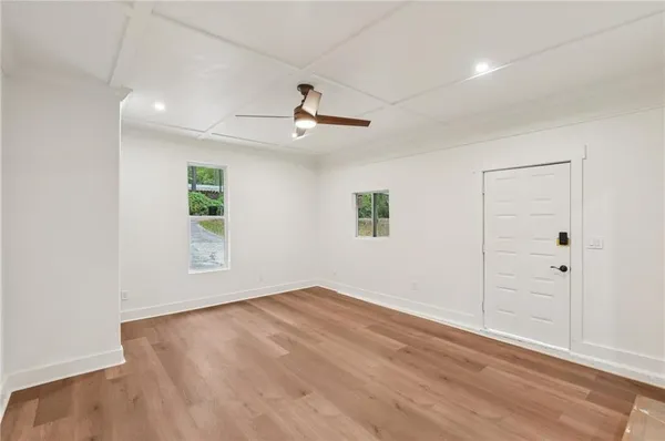 an empty room with wooden floor ceiling fan and windows