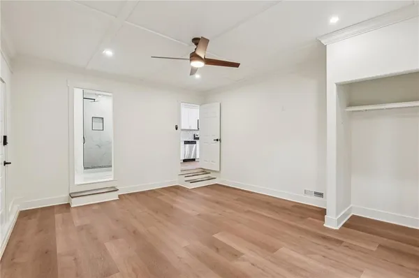 a view of empty room with wooden floor and fan