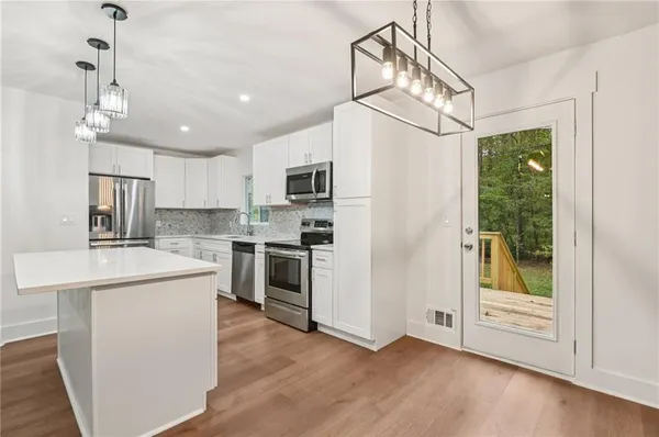a kitchen with stainless steel appliances a refrigerator a stove a sink dishwasher a oven with white cabinets and wooden floor
