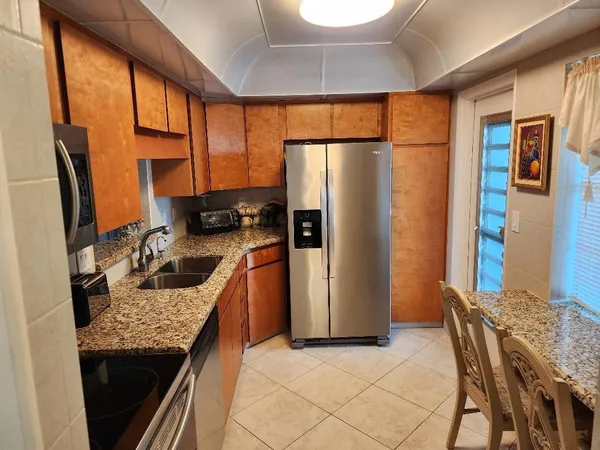 a kitchen with stainless steel appliances granite countertop a refrigerator a stove and a sink with wooden floor