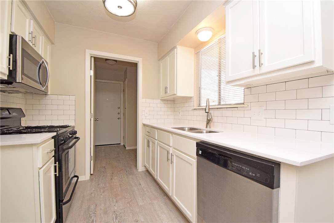 6400 Brookside Drive, Unit B Austin, TX 78723 - Photo 15 of 25 a kitchen with stainless steel appliances a sink dishwasher a stove and a refrigerator with wooden floor