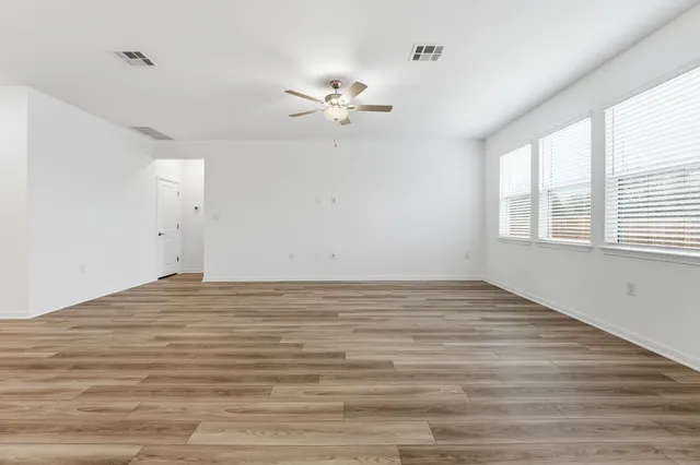 a view of empty room with wooden floor and fan