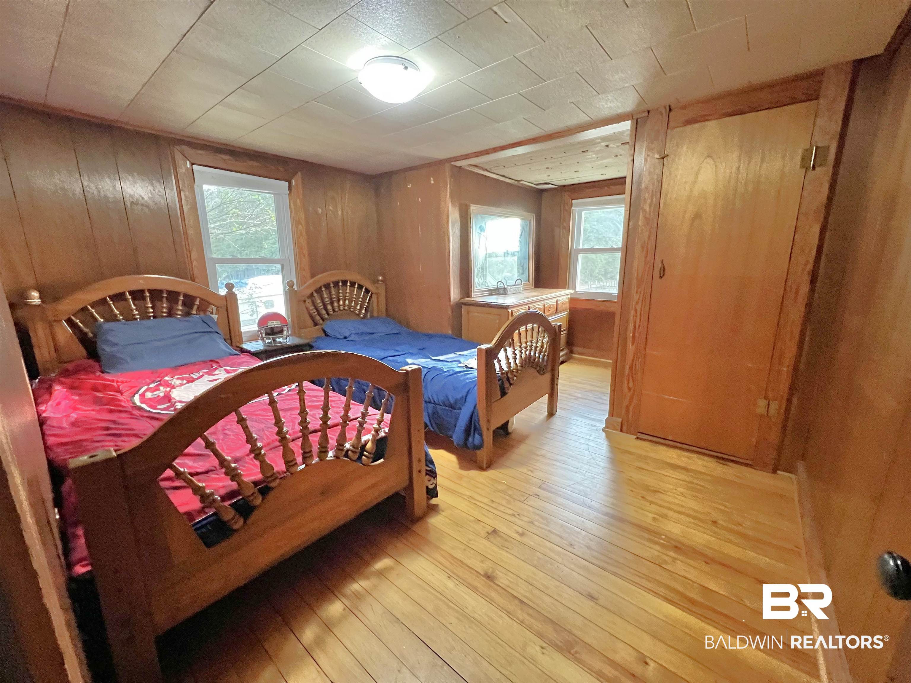 10283 Appleton Road Brewton, AL 36426 - Photo 18 of 18 Bedroom featuring wooden walls, multiple windows, and light wood-type flooring