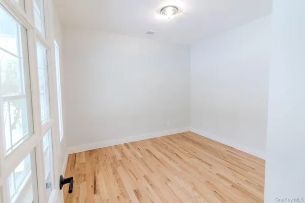 an empty room with wooden floor and windows