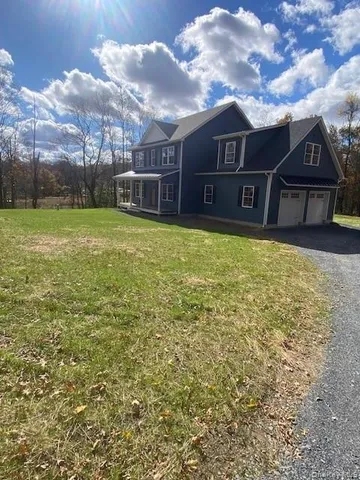 a view of a big house with a big yard plants and large tree