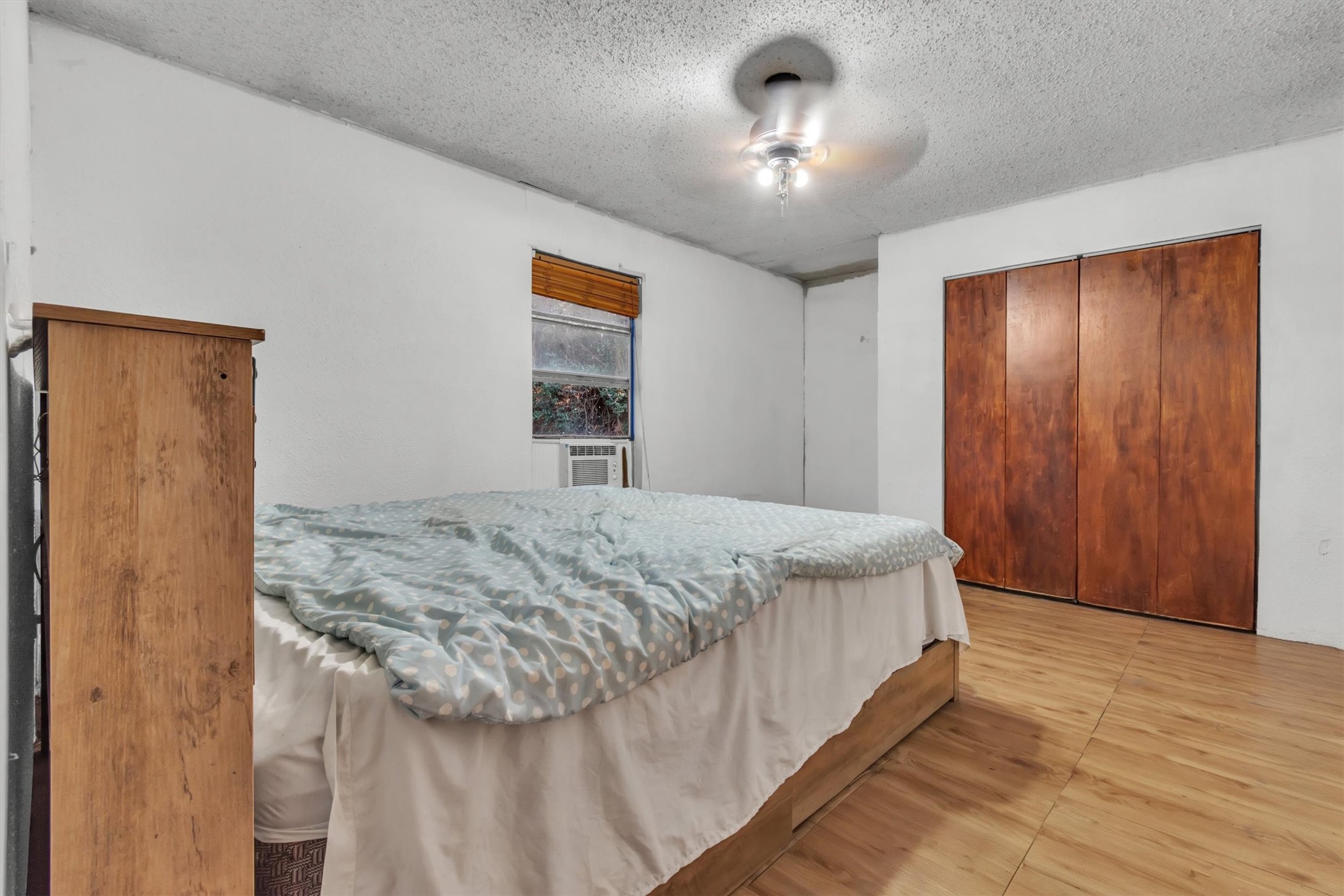 149 Wayside Drive Elgin, TX 78621 - Photo 11 of 24 Bedroom with a textured ceiling, a closet, a ceiling fan, and wood finished floors