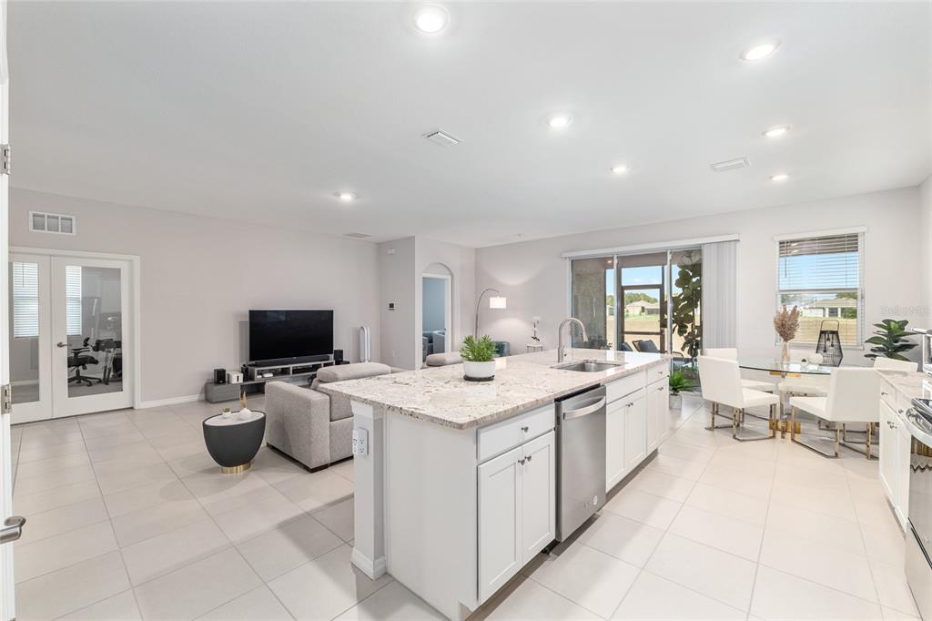 6243 Southwest 89th St Road Ocala, FL 34476 - Photo 29 of 57 a large white kitchen with a view of living room filled with furniture and flat screen tv